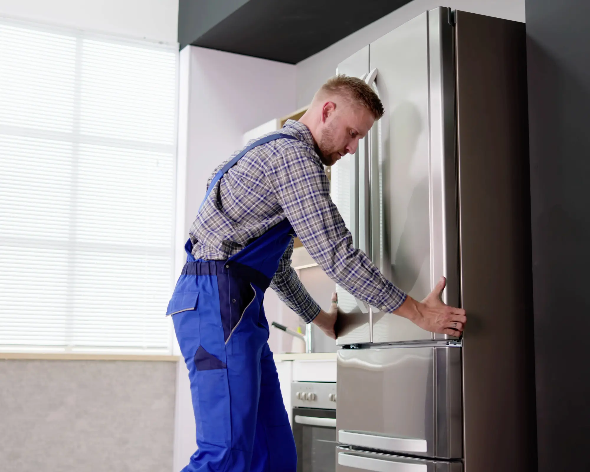 Appliance repair technician inspecting a stainless steel refrigerator during refrigerator repair service in San Antonio TX